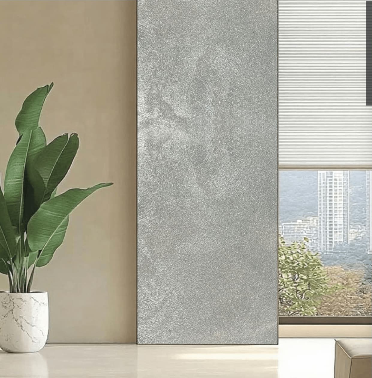 Satin Platinum metallic flexible wall panel installed as full-height interior feature panel beside floor-to-ceiling window – cool silver hammered foil surface with iridescent shimmer in natural daylight, white potted bird-of-paradise plant and city skyline view