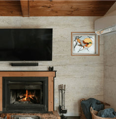 Toscano Wave travertine flexible stone veneer covering full living room wall – styled with wood beam ceiling, wall-mounted TV, lit fireplace and stained glass artwork