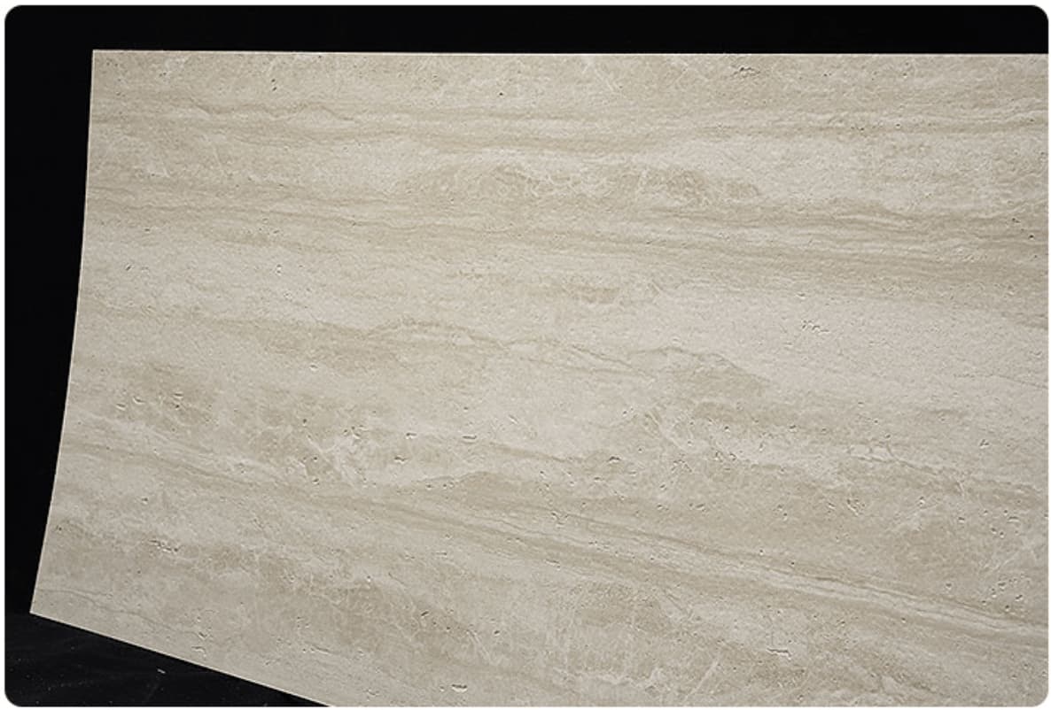 Cream travertine flexible stone panel – full sheet angled view showing warm cream surface with soft horizontal flowing grain on black background