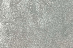  Satin Platinum metallic flexible wall panel – cool silver surface covered in fine hammered foil texture with subtle iridescent shimmer, flat lay close-up
